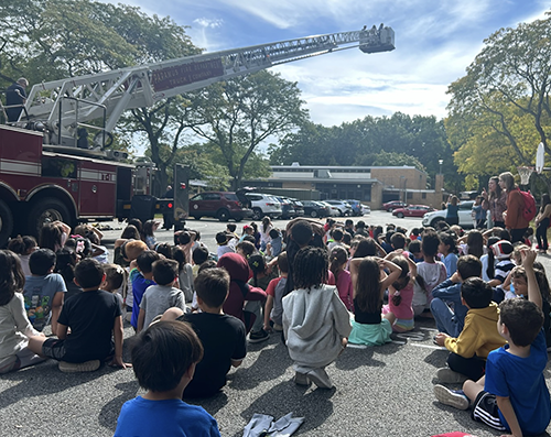 Students outside watching firefighters show them their truck