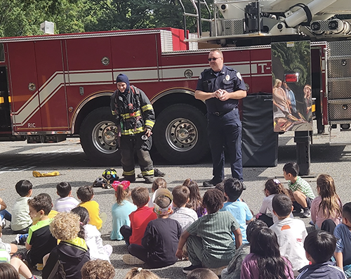 Firefighter talking to a group of students in front of a fire truck