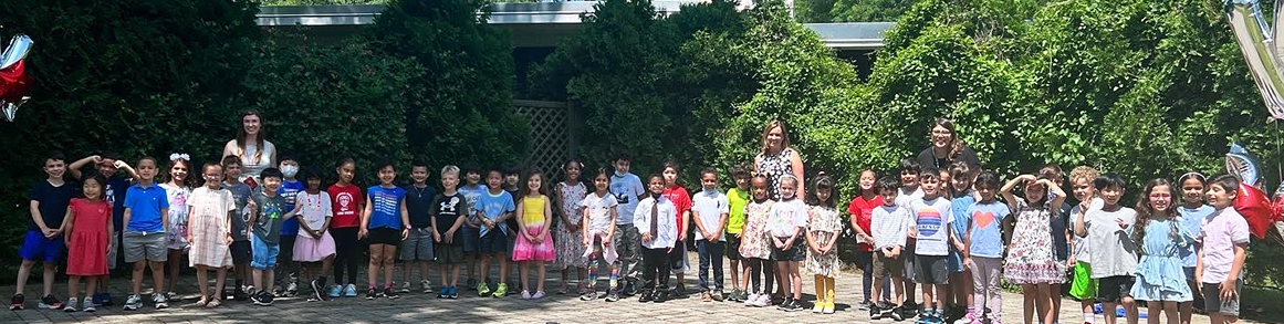 Kindergarten students in a row outside with teacher