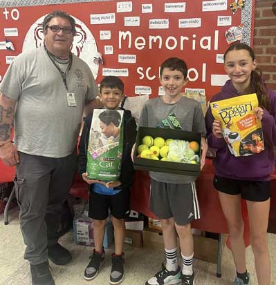 Students holding pet supplies next to a staff member