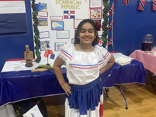 Pretty girl in a festive dress in front of the Dominican Republic display