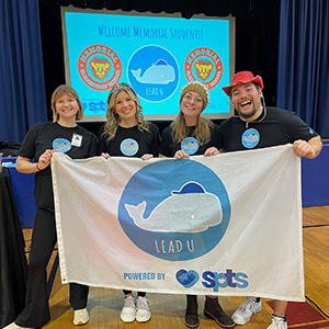 Adults holding a Lead U banner with a dolphin on it