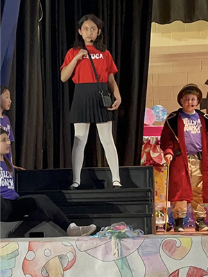 Students on stage with one standing up on some stairs