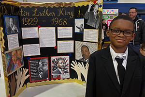 Student in front of their Martin Luther King Jr information presentation board