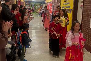 audiance clapping while students dressed for Lunar New Year walk down the hall