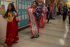 students dressed for Lunar New Year walk down the hall