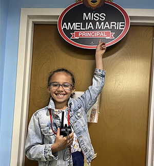 Amelia Marie looking at her principal for the day sign