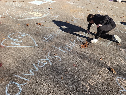 Memorial student writing positive affirmations in chalk out on the school playground