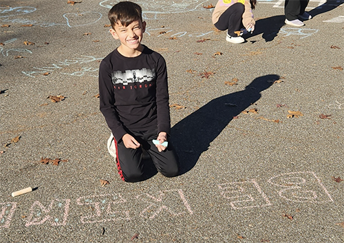 Memorial student posing for a picture with his BE KIND artwork