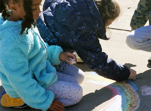 Memorial students drawing with chalk on the school playground