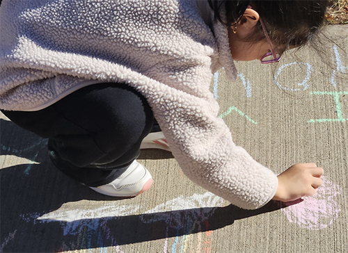 Close up of student drawing in chalk on the school playground