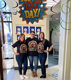Three happy teachers under 100 Day Celebration sign